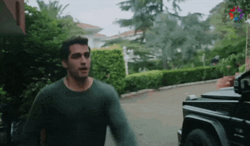 a man in a green sweater is standing in front of a black jeep