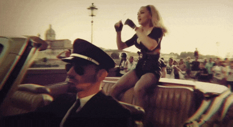 a woman is sitting on the back seat of a car while a man in a hat looks on