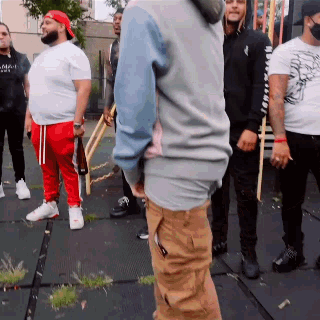 a man wearing a balmain shirt stands in a group of men