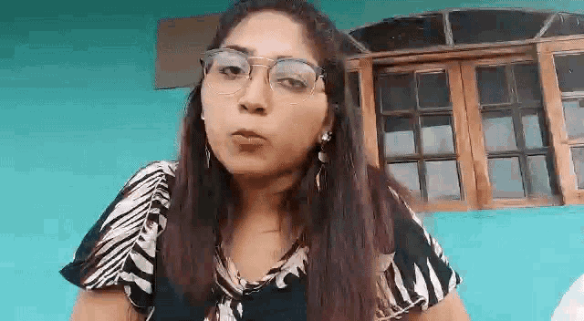 a woman wearing glasses and earrings is making a funny face .