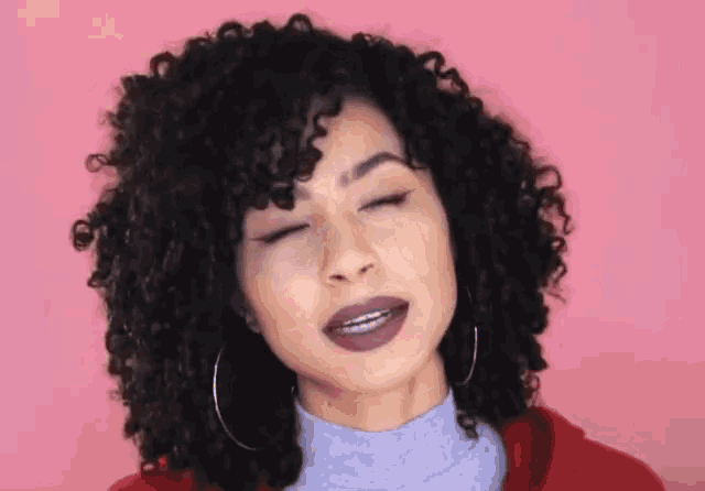 a woman with curly hair and braces is making a funny face with her eyes closed .