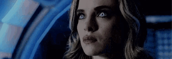 a close up of a woman 's face in a dark room with a blue background .