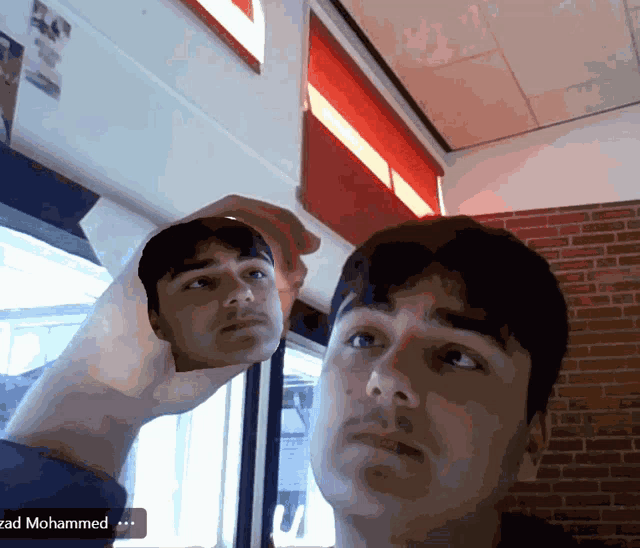 a man is looking at his reflection in a mirror and the name zadohammed is on the bottom right