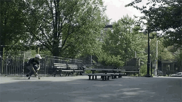 a person riding a skateboard in a park with benches and trees