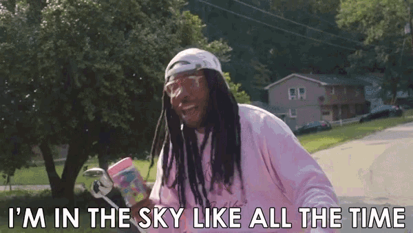 a man with dreadlocks wearing a pink sweatshirt and a white hat says i 'm in the sky like all the time