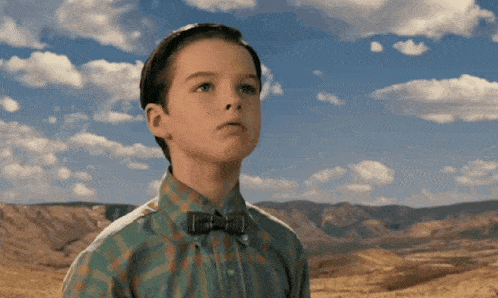 a young boy wearing a bow tie and a plaid shirt looks up at the sky