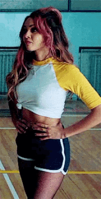 a woman wearing a crop top and shorts is standing on a basketball court .