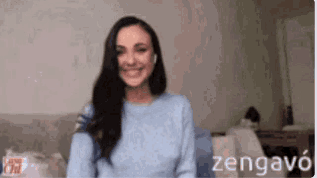 a woman wearing a blue sweater and headphones is smiling .