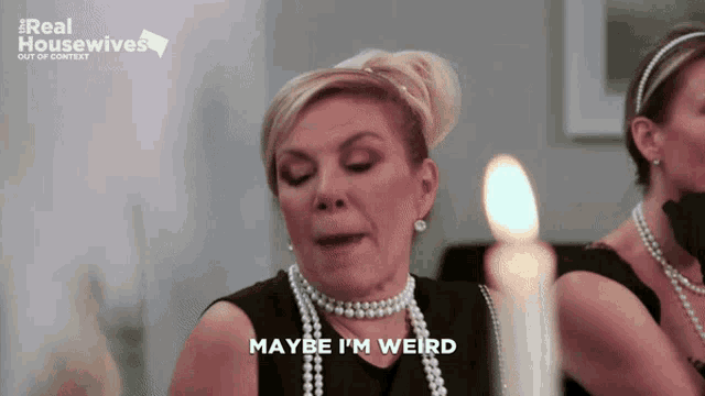 a woman wearing pearls and a black dress says " maybe i 'm weird "