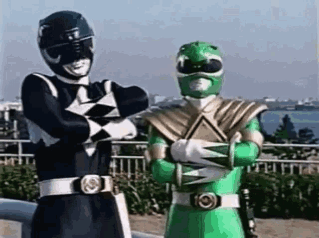 a black and green power ranger are standing next to each other with their arms crossed .