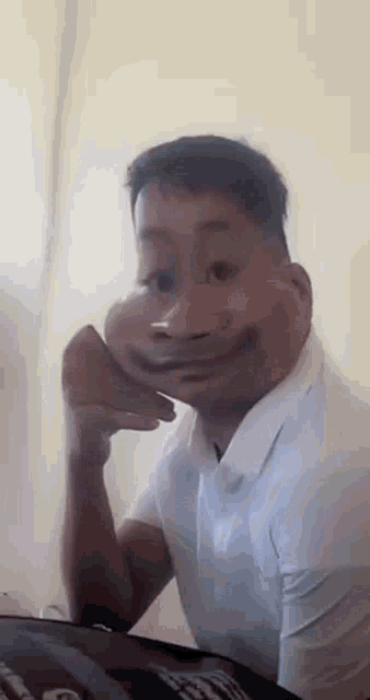 a man is making a funny face while sitting at a table .