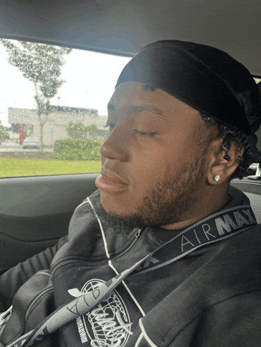 a man wearing an airmax headband is sleeping in a car with his eyes closed