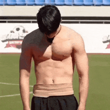 a shirtless man is standing on a soccer field with his hands on his head .