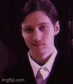 a young man wearing a suit and tie is looking at the camera .