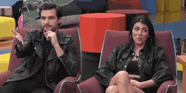 a man and a woman are sitting in chairs and the man is pointing