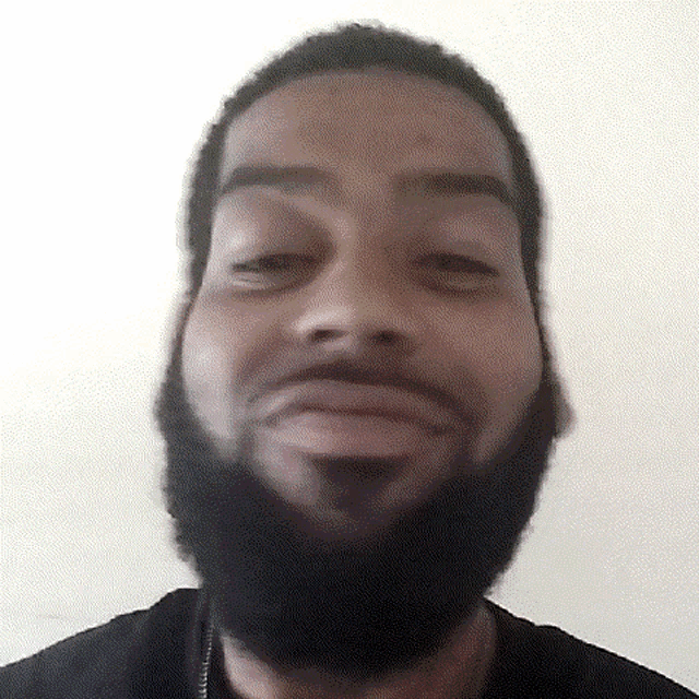 a man with a beard is making a funny face while looking at the camera .