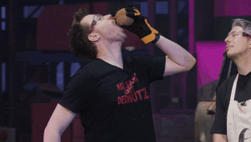a man wearing a black shirt that says mr. sam and dednutz drinks from a bottle