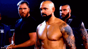 a shirtless man with a beard is standing in a ring with two other men