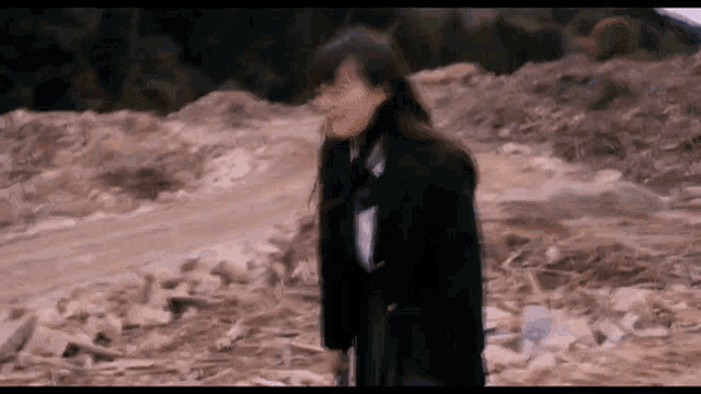 a girl in a school uniform is standing in a pile of rocks .