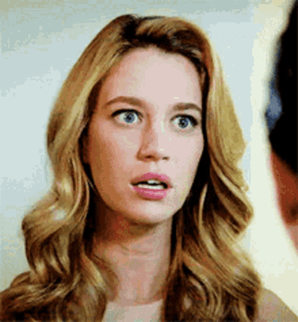 a woman with blonde hair is making a surprised face while looking at a man .