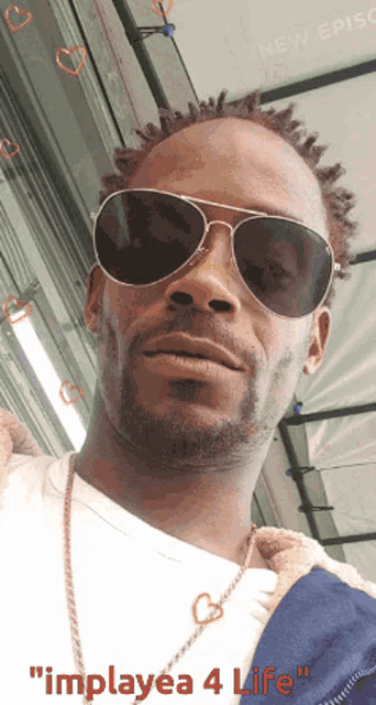 a man wearing sunglasses and a necklace with the words " implayea 4 life " on the bottom