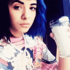 a woman with blue hair is holding a blender in her hand