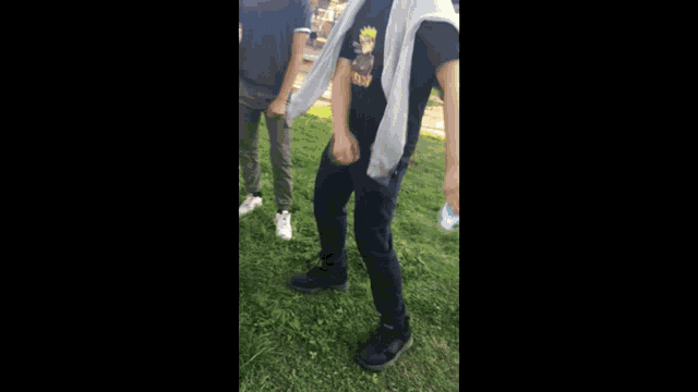 a man in a black shirt is standing in the grass with his hands in his pockets