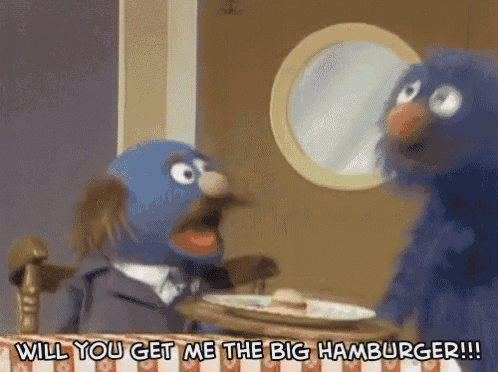 two sesame street characters are sitting at a table with a plate of food and the words " will you get me the big hamburger "