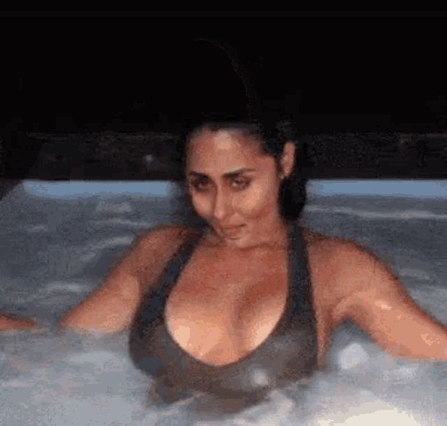 a woman is sitting in a hot tub with her breasts visible .