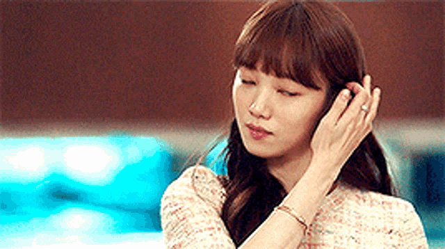 a woman is adjusting her hair while wearing a bracelet and a ring .