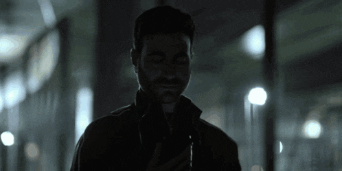 a man in a dark room looking at his cell phone