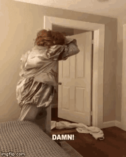 a woman in a satin robe is standing in front of a door that says damn on it