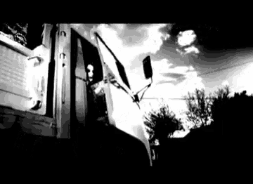 a black and white photo of a man in the driver 's seat of a truck