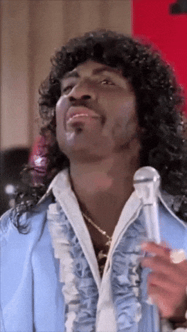 a man with long curly hair is holding a microphone