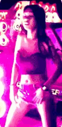 a woman in a crop top and shorts is dancing in front of a sign that says er