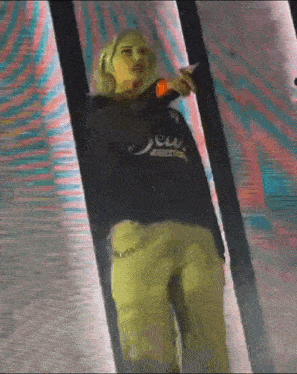 a woman is standing on a stage holding a microphone and a cell phone .