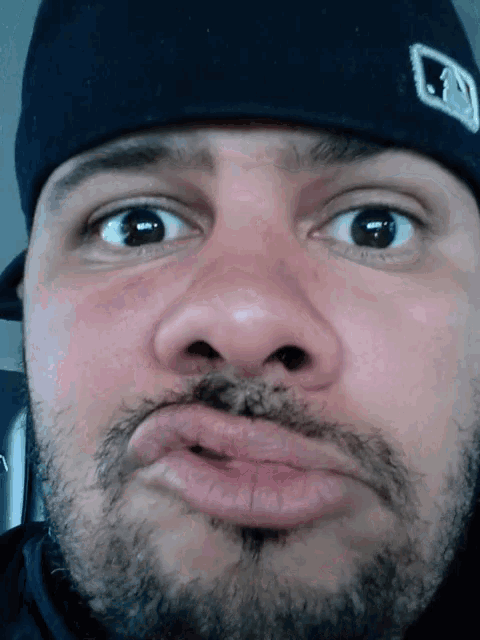 a close up of a man 's face wearing a hat with a l on it