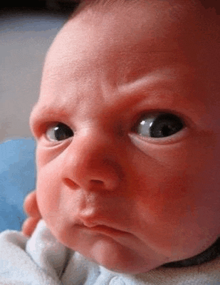 a baby is making a funny face with his eyes closed .
