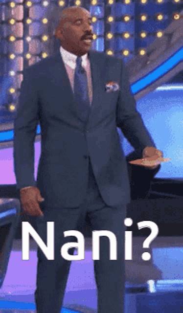 a man in a suit and tie is standing in front of a sign that says " nani "