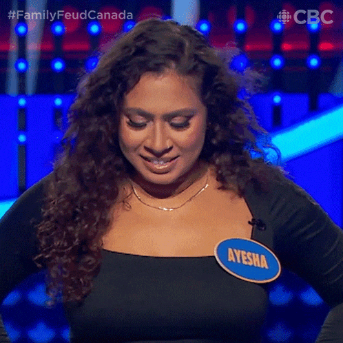 a woman with curly hair is wearing a name tag that says ayesha and is smiling .