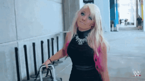a woman with blonde hair and pink highlights is walking down a sidewalk with a walker .