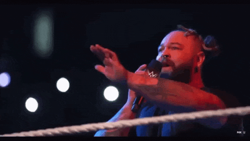 a man in a wrestling ring is giving a thank you speech .