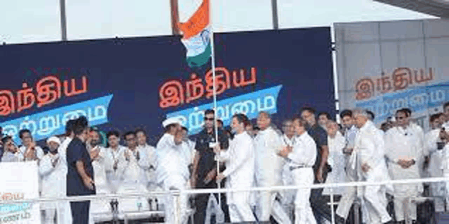 a group of people are standing in front of a large banner holding a flag .
