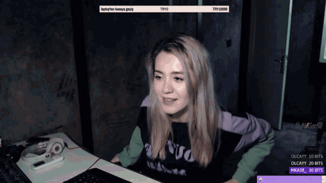 a girl is sitting at a desk with a laptop and a purple shirt that says ' nsvo ' on it
