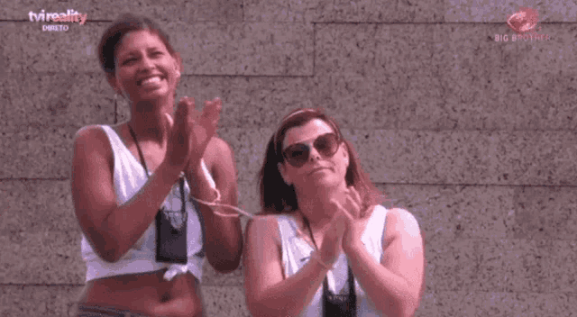 two women are clapping in front of a tvreality logo