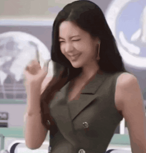 a woman in a green dress is smiling and making a funny face .