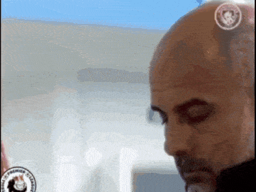 a man with a bald head and a beard is looking at the camera with his eyes closed .