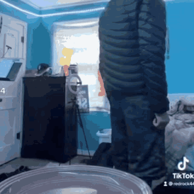 a man in a black jacket is standing in a room with blue walls ..