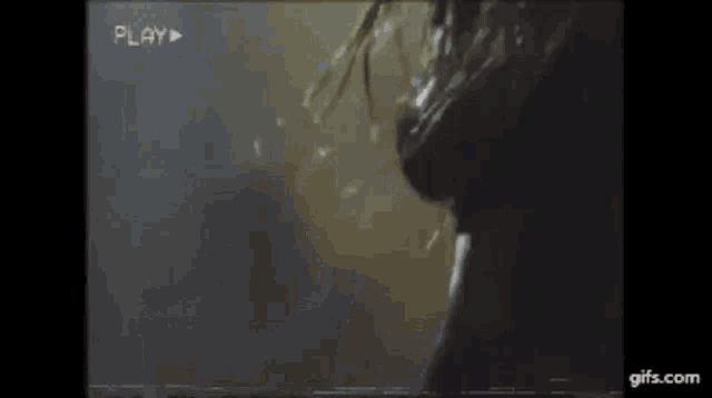 a woman is taking a shower in a dark room with a play button on the bottom of the screen .