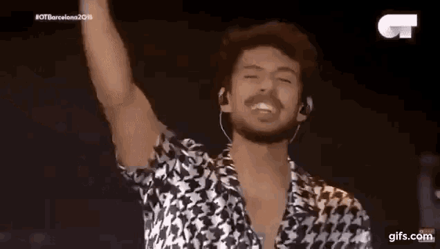 a man with a beard is standing on a stage with his hand in the air .